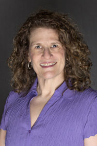 Headshot of Meryl with curly hair and a lavender button up shirt