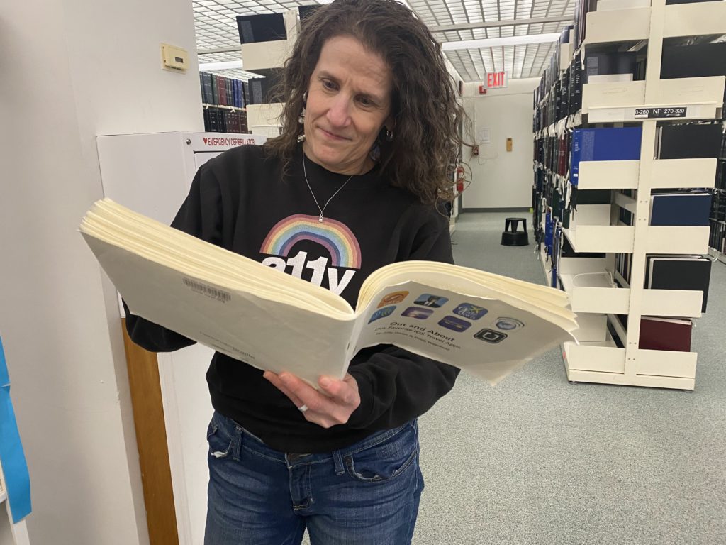 With a Braille book open, Meryl examines its pages
